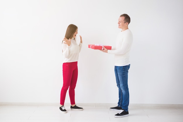Ludzie, Boże Narodzenie, urodziny, święta i koncepcja Walentynki - Przystojny mężczyzna daje swojej dziewczynie pudełko na białym tle.