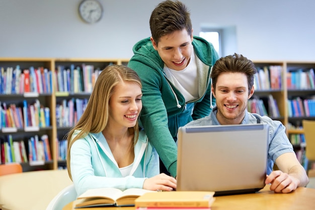 ludzie, edukacja, technologia i koncepcja szkoły - szczęśliwi uczniowie z siecią laptopów w bibliotece