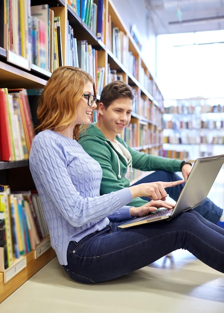 ludzie, edukacja, technologia i koncepcja szkoły - szczęśliwi uczniowie z siecią laptopów w bibliotece