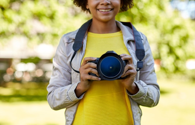 Ludzie, Fotografia, Technologia, Wypoczynek I Styl życia - Zbliżenie Szczęśliwej Młodej Afroamerykańskiej Fotografki Z Aparatem Cyfrowym W Letnim Parku