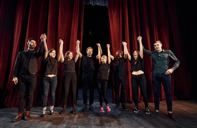 Ludzie kłaniający się publiczności Grupa aktorów w ciemnych ubraniach na próbie w teatrze