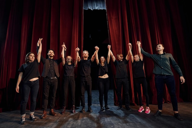 Zdjęcie ludzie kłaniający się publiczności grupa aktorów w ciemnych ubraniach na próbie w teatrze