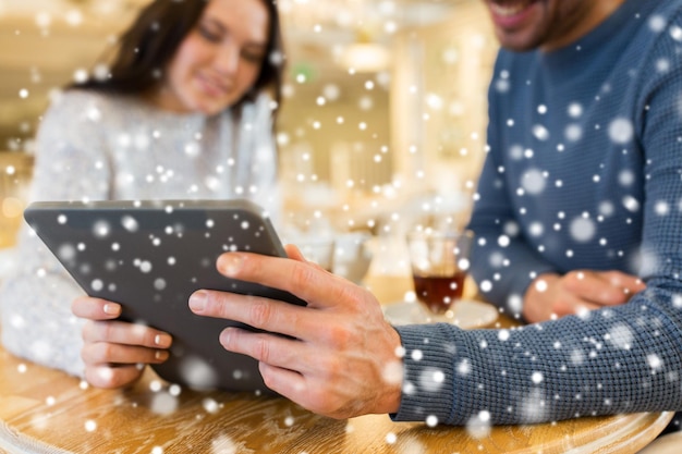 ludzie, komunikacja i randki koncepcja - zbliżenie szczęśliwej pary z komputerem typu tablet w kawiarni lub restauracji