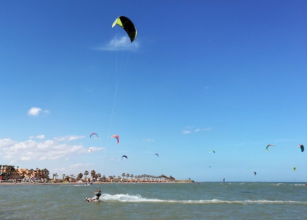 Zdjęcie ludzie latają paragliderem na plaży na tle nieba