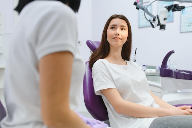 Ludzie medycyna stomatologia i koncepcja opieki zdrowotnej szczęśliwa dentystka z cierpliwą dziewczyną rozmawiającą w biurze kliniki dentystycznej