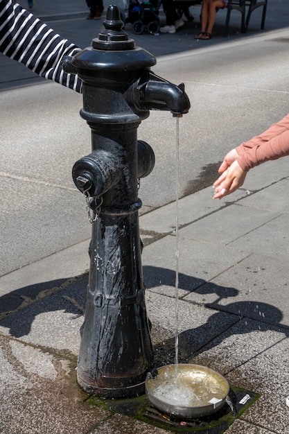 Ludzie na ulicy w Wiedniu piją wodę z kolumny wodnej