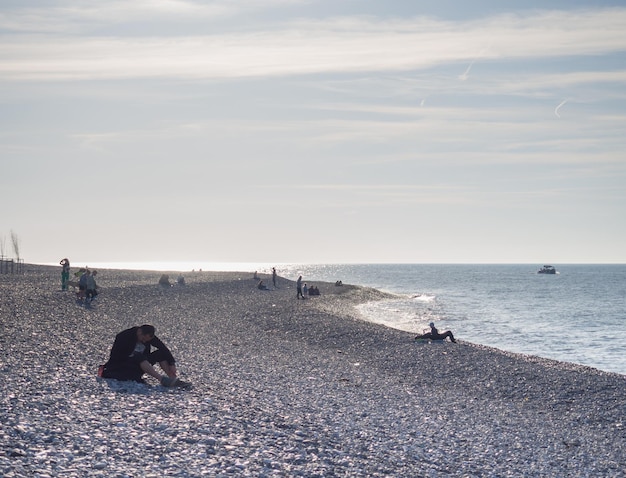 Ludzie na wiosennej plaży żwirowej Wakacje na plaży Relaks na morzu Skaliste wybrzeże Plaża żwirowa Łodzie na wodzie