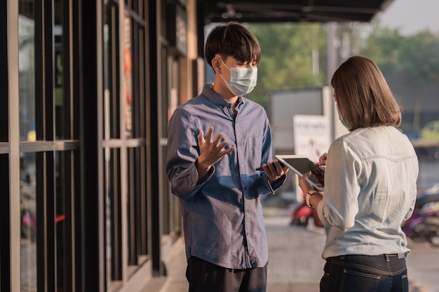 Ludzie noszą maskę na twarzy, chroniąc komunikację koronawirusa za pomocą technologii tabletów