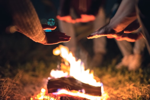 Ludzie ogrzewający ręce przy ognisku. wieczorna pora nocna