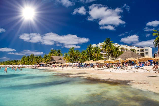 Ludzie opalają się na białej, piaszczystej plaży z parasolami bungalow bar i palmami kokosowymi turkusowe morze karaibskie Wyspa Isla Mujeres Morze Karaibskie Cancun Jukatan Meksyk