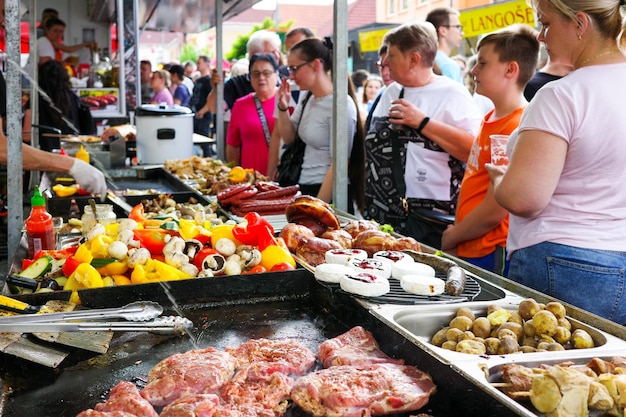 Ludzie patrząc na grillowane mięso na rynku z przekąskami