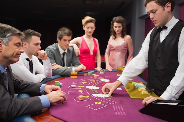 Ludzie patrząc na rozdającego rozdającego karty blackjack w kasynie