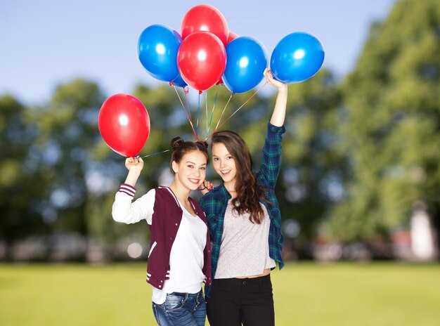 ludzie, przyjaciele, nastolatki, wakacje i koncepcja imprezy - szczęśliwe uśmiechnięte ładne nastolatki z balonami z helem na tle letniego parku