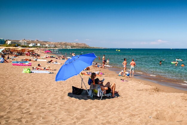 Ludzie relaksujący się na piaszczystej plaży w ośrodku Faliraki na wyspie Rodos w Grecji