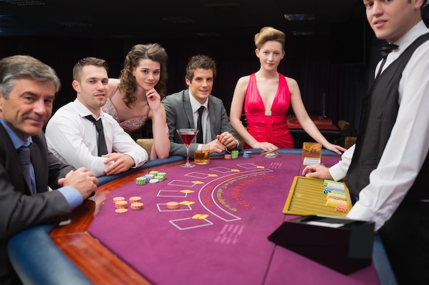 Ludzie siedzący przy stole blackjack, uśmiechając się do kasyna