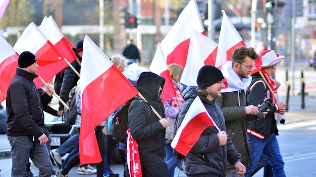 ludzie trzymają flagi, a na jednej z nich znajduje się czerwono-biały trójkąt.