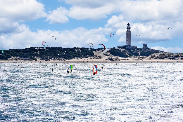Ludzie uprawiający kitesurfing na plaży Los Caos de Meca, obok latarni morskiej Trafalgar.