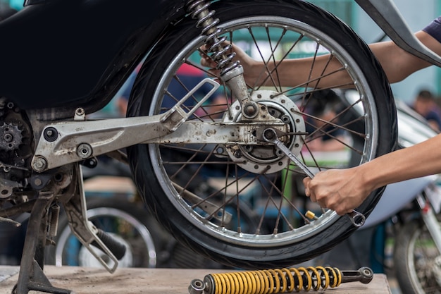 Ludzie używają rąk naprawiają motocykl Użyj klucza do pracy