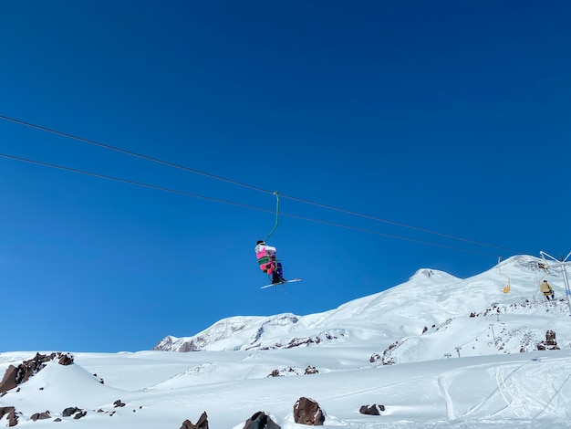 Zdjęcie ludzie w garniturach sportowych podnoszący się na windzie narciarskiej w górach