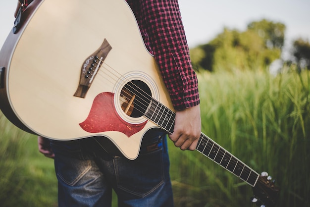 Zdjęcie ludzie w koszuli w kratę trzymający gitarę akustyczną na farmie zbliżenie