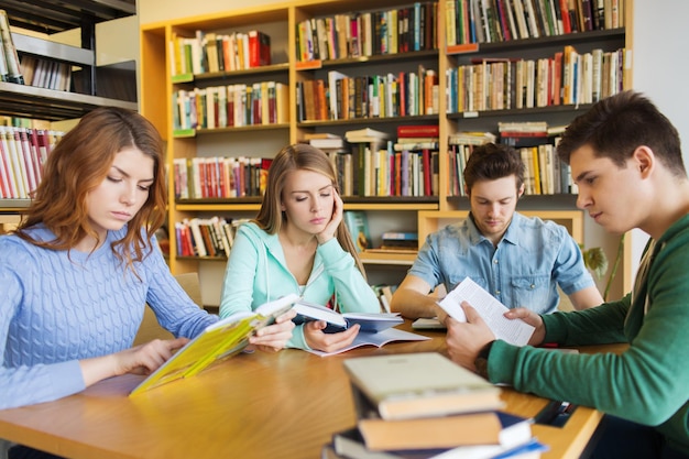 ludzie, wiedza, edukacja, literatura i koncepcja szkoły – studenci czytający książki i przygotowujący się do egzaminów w bibliotece