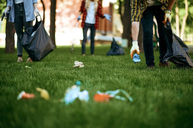 Ludzie zbierają plastikowe śmieci w workach w parku, wolontariusze