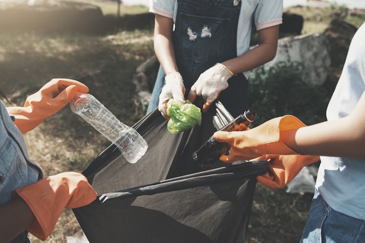 Zdjęcie ludzie zbierają śmieci i wkładają je do plastikowej czarnej torby do czyszczenia w parku