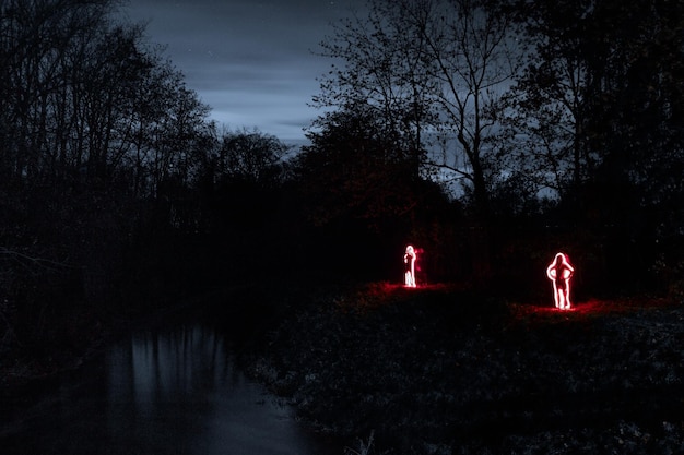 Zdjęcie ludzie ze świetlnym malowaniem na polu w nocy w lesie