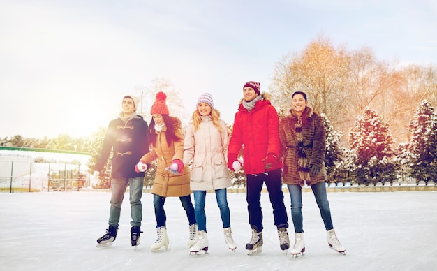 ludzie, zima, przyjaźń, sport i rekreacja koncepcja - szczęśliwi przyjaciele łyżwiarstwo na lodowisku na świeżym powietrzu