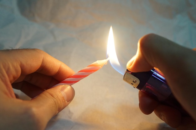 Zdjęcie ludzka ręka paląca świecę z zapalniczką
