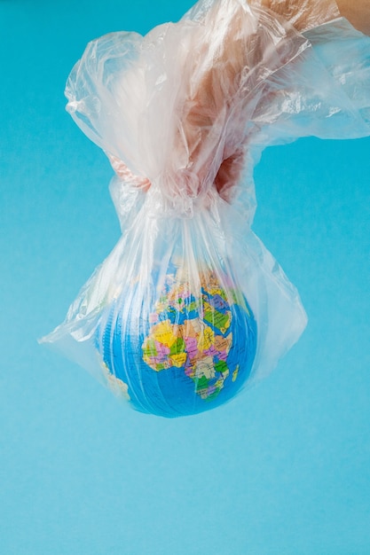 Zdjęcie ludzka ręka trzyma planetę ziemię w plastikowej torbie. pojęcie zanieczyszczenia odpadami z tworzyw sztucznych. globalne ocieplenie spowodowane efektem cieplarnianym.