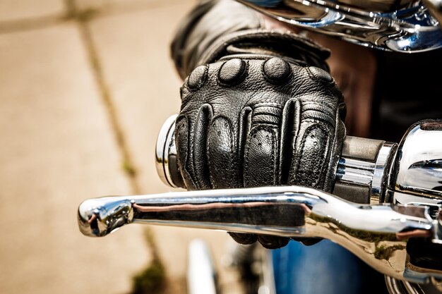 Ludzka ręka w motocyklowych rękawicach wyścigowych trzyma kontrolę przepustnicy motocykla. Ochrona rąk przed upadkami i wypadkami.