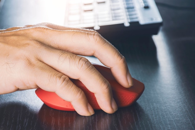 Zdjęcie ludzka ręka za pomocą myszy komputerowej z czerwonym kolorem na biurku