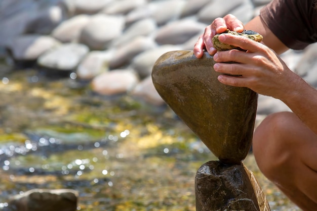 Zdjęcie ludzkie ręce budują na wodzie kopiec kamieni. równowaga i medytacja