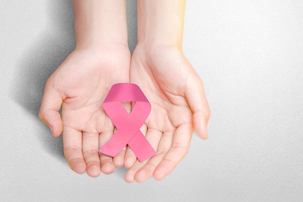 Ludzkie ręce pokazano różową wstążkę świadomości. Świadomość raka piersi