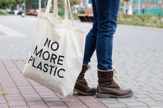 Ludzkie stopy w dżinsach i butach z torbą z napisem No more plastic