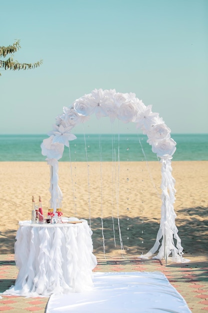 Łuk ceremonii ślubnej z białymi kwiatami na tle morza