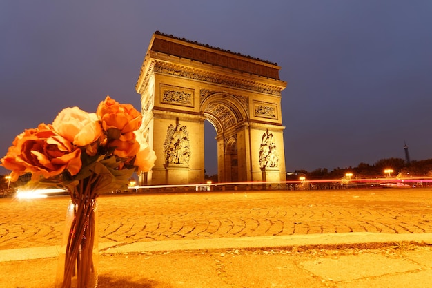 Łuk Triumfalny wieczorem i pęczek kwiatów na pierwszym planie Paryż Francja