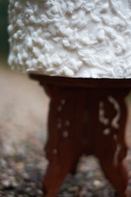 Luksusowa biała koronkowa tort weselny, ozdobiona białymi ornamentami na stojaku na weselu