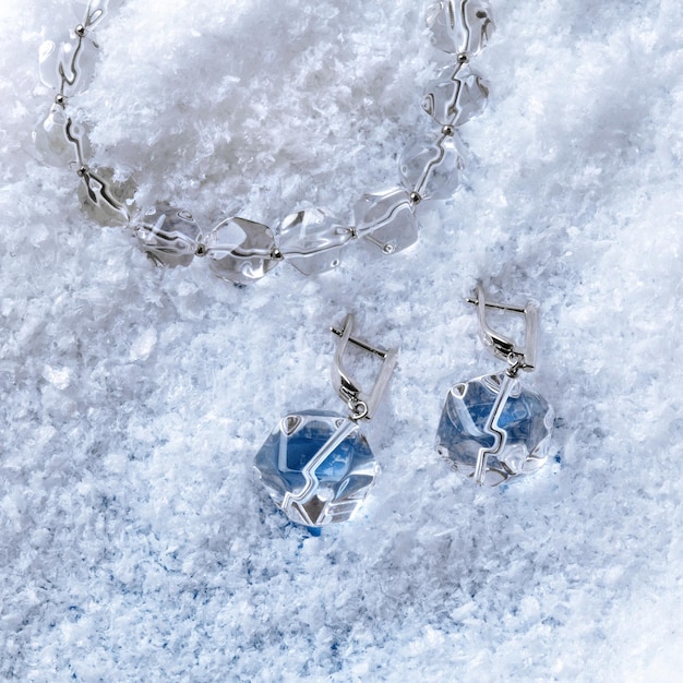 Luksusowa elegancka bransoletka i kolczyki z kryształowymi kryształkami na białym tle śniegu. Strzał z bliska. Widok z góry