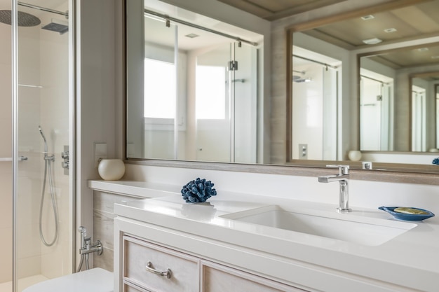 Luksusowa łazienka z dużym lustrem z niezwykłym wielokrotnym odbiciem Przestronna strefa prysznica ze szklaną balustradą Jasne światło słoneczne w ciągu dnia oświetla ogromną łazienkę ukazując jej splendor