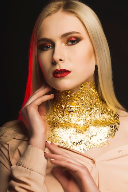 Luksusowa modelka z jasnym wieczorowym makijażem i złotą folią na szyi