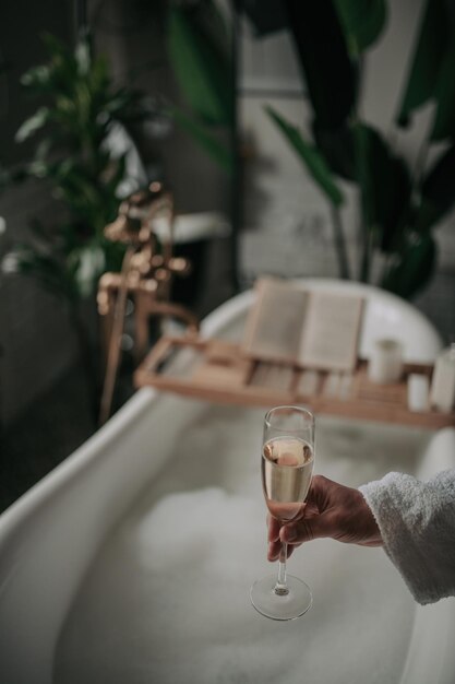 Luksusowa nowoczesna łazienka w stylu eko z owalną wanną i kieliszkiem do szampana przy naturalnym oświetleniu