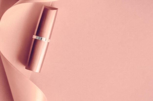 Luksusowa szminka i jedwabna wstążka na różowo różowym świątecznym tle makijażu i kosmetykach flatlay do projektowania produktów marki kosmetycznej