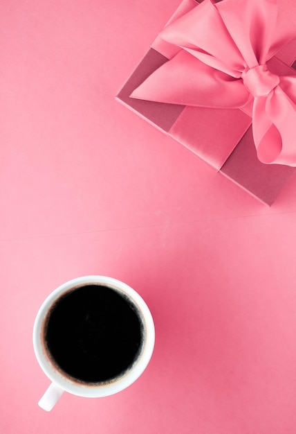 Luksusowe pudełko i filiżanka kawy na różowym tle flatlay na romantyczną świąteczną niespodziankę rano
