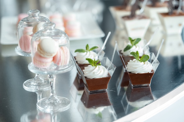Luksusowe słodkie desery na weselu. Makaroniki i deser czekoladowy w szklanych formach