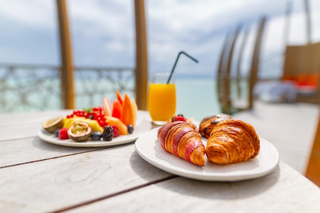 Luksusowy hotel przy basenie, restauracja na świeżym powietrzu na plaży. Nastrojowe śniadanie z sokiem z rogalika