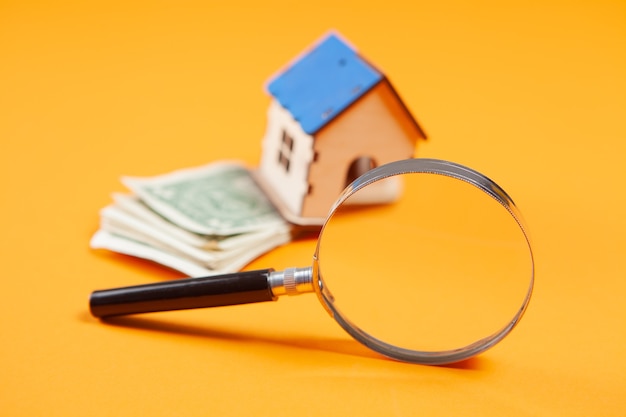 Lupa, dom i pieniądze na żółtej powierzchni. koncepcja badania kosztów domu house