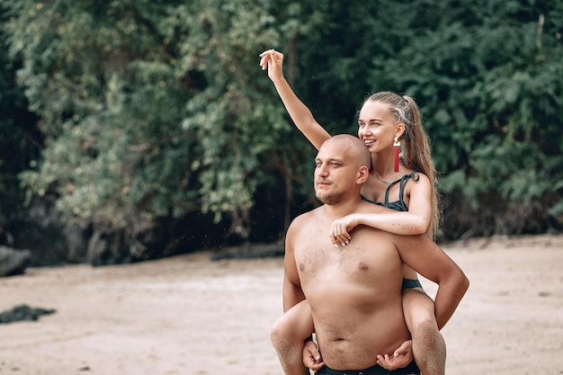 Łysy facet niosący dziewczynę na plecach, na plaży, na zewnątrz. Phuket. Tajlandia.