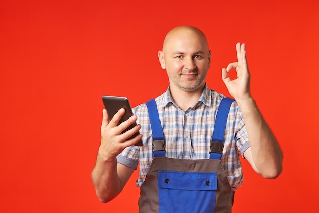 Łysy mężczyzna w garniturze trzyma telefon i pokazuje gest ok